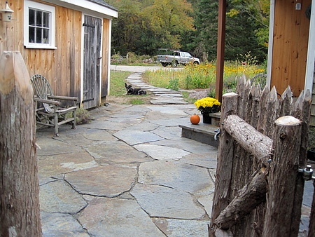 The client installed a new rustic fence that is quite fitting with the patio. Off in the distance, past the stepping stone walkway, the new parking area can be seen.
