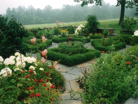Another view of the Worthington, MA formal garden with manicured box hedges, carefully built stone wall, and ornamental birdbath.